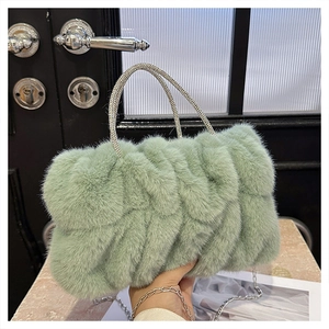 Détail d'un sac à main en peluche vert clair avec poignées en strass et chaîne argentée