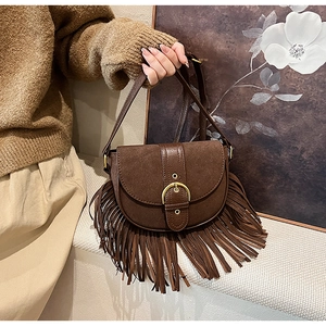 Detailed view of vintage brown saddle bag featuring long leather tassels and suede texture