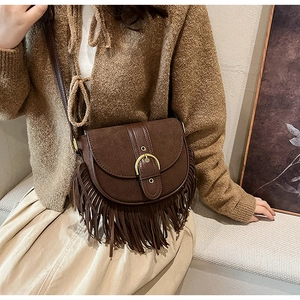 Detail shot of the vintage brown matte saddle bag with long tassels and a gold metal buckle