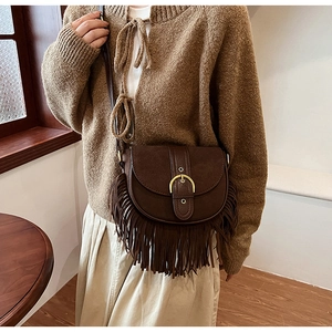 Detailed close-up of retro brown saddle bag with fringe tassels and gold horseshoe buckle