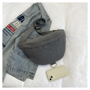 Detailed macro view of grey corduroy texture and gold ring charm on a crossbody chest bag