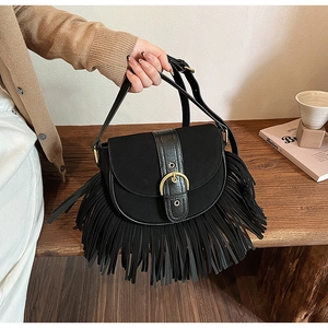 Detail of vintage black saddle bag featuring matte suede and golden horseshoe buckle