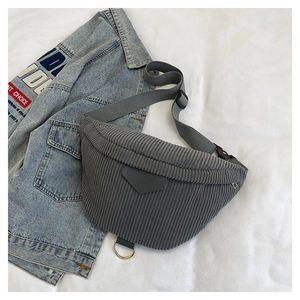 Detail of gray corduroy waist bag showing texture, zip closure, and adjustable strap