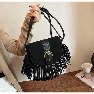 Detail of vintage black saddle bag with gold horseshoe buckle and long hanging tassels