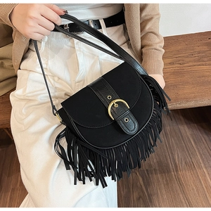 Macro detail of black saddle bag with fringe trim and golden horseshoe metal buckle