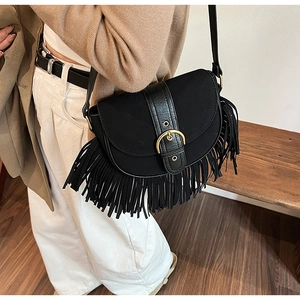 Close-up of black tassel saddle bag with bronze buckle and vintage suede texture
