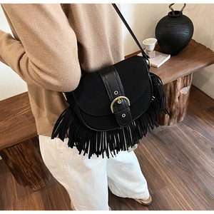 Bohemian black matte saddle bag with long fringe and gold buckle shown on a model