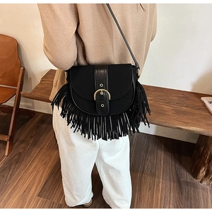 Detail of a black vintage saddle bag with matte leather finish and long fringe tassels