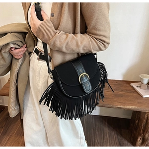Detail of black saddle bag with fringe trim, matte texture and metallic buckle closure