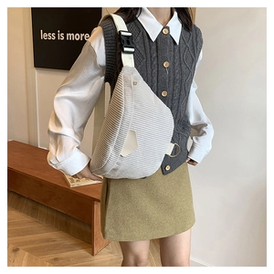 Detail of light gray corduroy crossbody bag with adjustable wide strap and metal rings