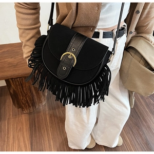 Detail of black suede saddle bag featuring long tassels and gold ring buckle