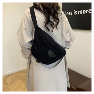Detail of black corduroy belt bag on model wearing a beige trench coat for autumn style