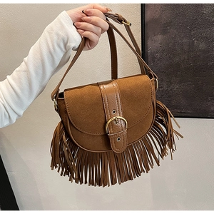 Detail of vintage brown tassel crossbody saddle bag with gold buckle and suede texture
