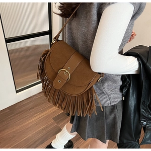 Detailed view of the brown saddle bag featuring long tassels and vintage golden buckle