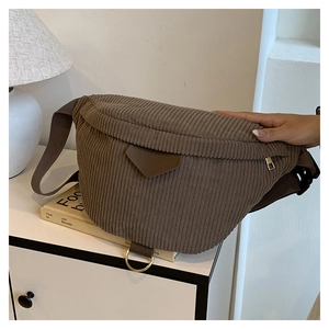 Detail of dark brown corduroy belt bag with leather patch and metallic zipper accent