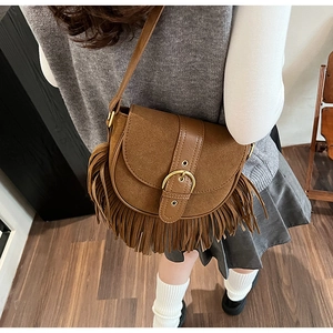 Detailed view of vintage brown suede saddle bag with long fringe and golden buckle
