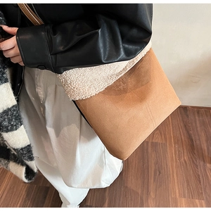 Dettaglio di una borsa in camoscio marrone e pelliccia sintetica bianca indossata da modella