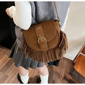 Detail of vintage brown suede saddle bag with fringe tassels and gold buckle