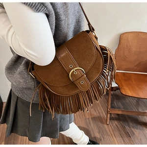 Close-up of vintage brown suede saddle bag with long tassels and gold metallic buckle