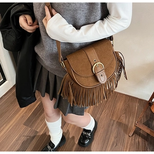 Close-up of vintage brown tassel saddle bag in matte texture with adjustable shoulder strap
