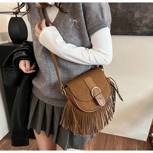 Close-up of vintage brown suede saddle bag with fringe tassels and gold metal buckle