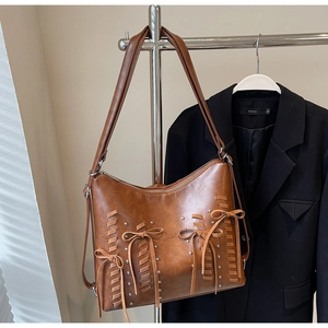 Dettaglio della borsa tote marrone con rivetti argentati e fiocco decorativo fine
