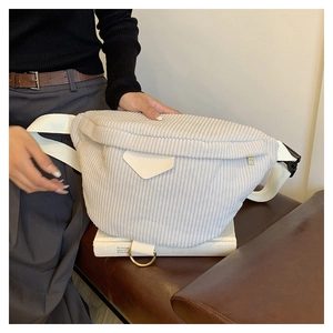 Detail of light grey corduroy belt bag with creamy leather patch and gold metal ring accent