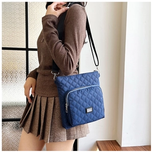 Blue quilted nylon crossbody bag featuring front zipper pocket and adjustable strap