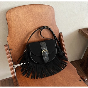 Close-up of black suede saddle bag featuring long fringe and a gold horseshoe buckle