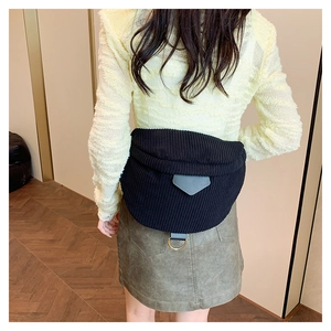 Detail view of black corduroy belt bag with gray leather buckle on a casual outfit