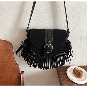 Close-up of black fringe saddle bag with matte finish and gold circular buckle detail