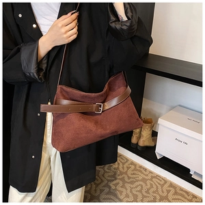 Détail d'un sac cabas rétro en daim bordeaux avec sangles en cuir brun et boucles argentées