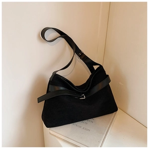 Détail d'un sac bandoulière en daim noir mat avec sangle en cuir et boucle métallique