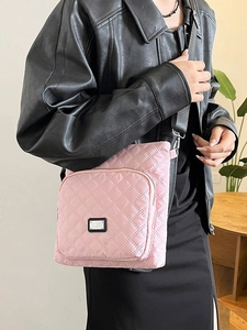 Pink quilted crossbody bag with adjustable strap worn by model in a minimalist setting