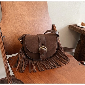 Detail of vintage brown suede crossbody bag with decorative fringe and gold buckle