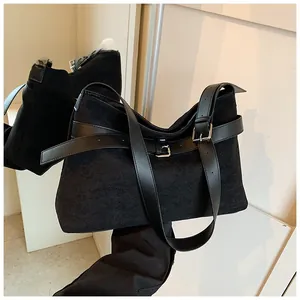 Détail macro du sac à main en daim noir mat avec boucle argentée et décoration