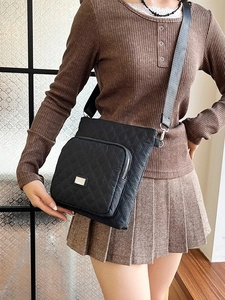 Black quilted nylon crossbody bag with diamond stitch pattern and silver metal hardware