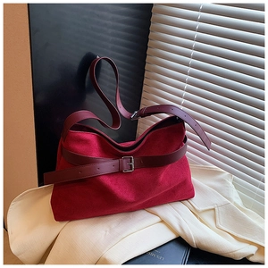 Détail du sac fourre-tout en daim rouge avec lanières en cuir marron et boucle argentée