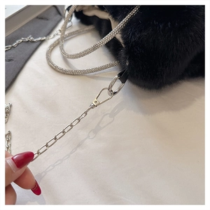 Détail du sac en peluche noire avec poignées en strass brillants et bandoulière chaîne