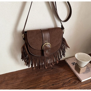 Detail view of vintage brown suede saddle bag with fringe tassels and metal buckle