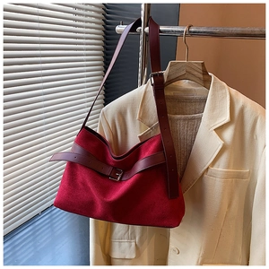 Détail d'un sac cabas en daim bordeaux avec bandoulières en cuir et boucle argentée