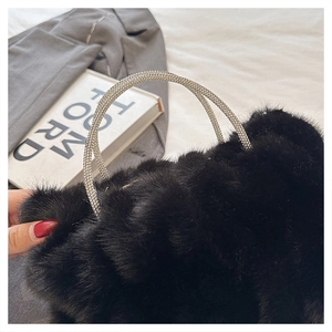 Gros plan sur un sac en fausse fourrure noire avec poignées ornées de strass argentés