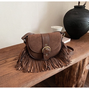 Close-up of vintage dark brown fringe saddle bag with matte finish and gold buckle details