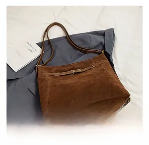 Detailed close-up of dark brown suede shoulder bag with adjustable belt buckle decor