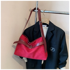 Détail du sac cabas en daim rouge avec lanières en cuir et boucle métallique