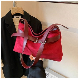 Vue détaillée de la texture du daim rouge et des boucles en métal argenté poli sur le sac