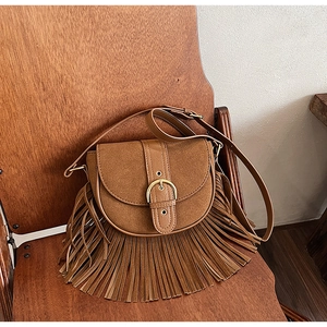 Close-up of vintage brown suede saddle bag with long fringe and metal buckle detail