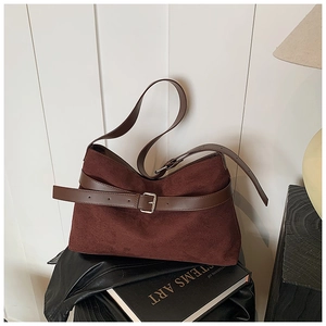 Gros plan sur un sac cabas en daim marron avec bandoulière et boucle argentée