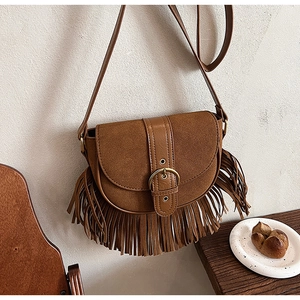 Macro view of vintage brown saddle bag with long leather tassels and suede details