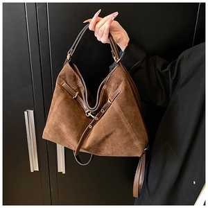 Detailed view of dark brown suede leather texture and antique bronze metal hardware on bag